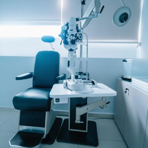A modern optometry examination room with an ophthalmic chair and slit lamp.
